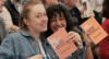 Roche Content Creator Masterclass 2025: Das Bild zeigt zwei junge Frauen auf der Veranstltung, die lachend ein Heft mit CCMC-Logo in die Kamera halten.