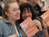 Roche Content Creator Masterclass 2025: Das Bild zeigt zwei junge Frauen auf der Veranstltung, die lachend ein Heft mit CCMC-Logo in die Kamera halten.
