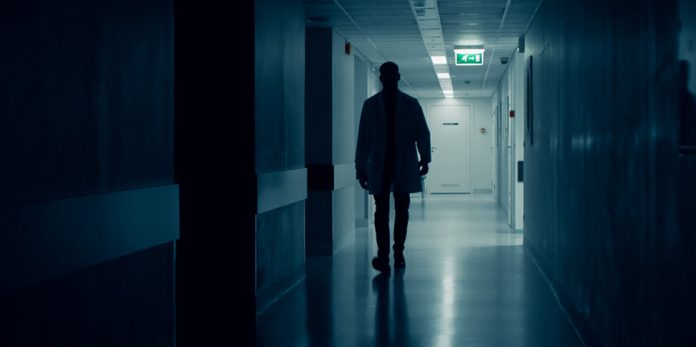 Arzt geht über dunklen Flur eines Krankenhauses. Honorararzt.